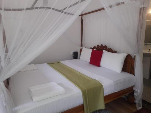 a bedroom with a white bed with a canopy at Tranquility guest house in Hikkaduwa