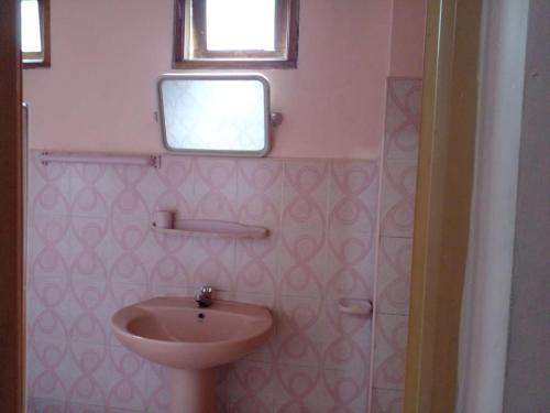 a pink bathroom with a sink and a window at Silent Night Homestay in Ella