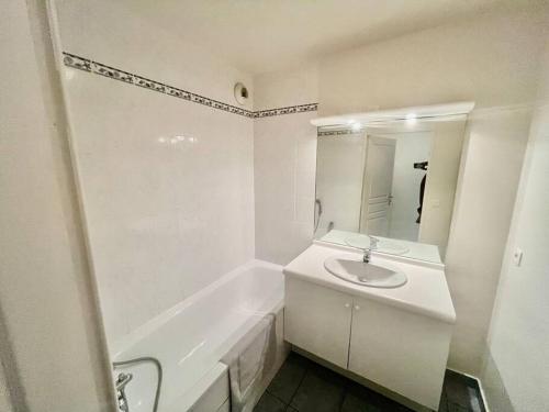 een witte badkamer met een wastafel en een bad bij Le Sept avec parking, transfert in Vaires-sur-Marne