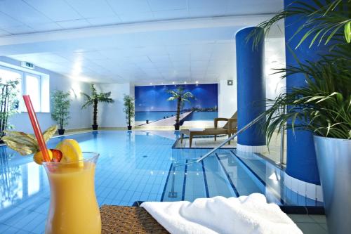 a swimming pool with a drink on a table at Hotel Dänischer Hof Altenholz by Tulip Inn in Altenholz
