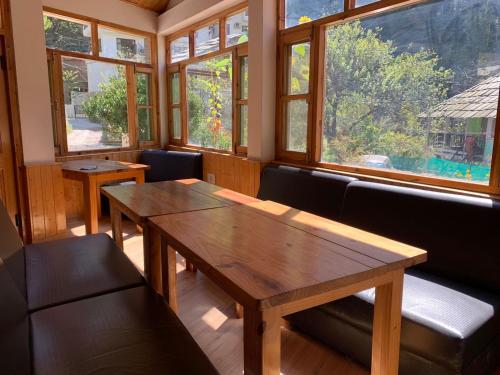 a room with a wooden table and benches and windows at Purnima Guest House, Old Kasol in Kasol