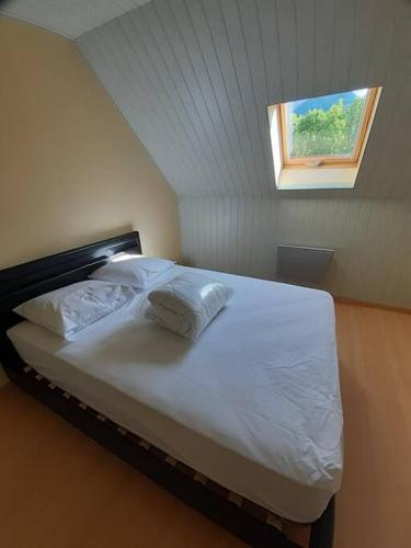 une chambre avec un grand lit blanc avec une fenêtre dans l'établissement Maison Cosy, cœur de village, à École