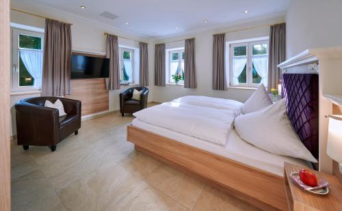 ein großes Schlafzimmer mit einem großen Bett und einem Stuhl in der Unterkunft Ferienwohnungen im Bonnschloessl in Bernau am Chiemsee