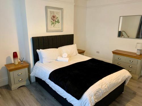 a bedroom with a bed with a black and white comforter at Blossom Holiday Lets - 3 Bed Bensham Apartment in Gateshead