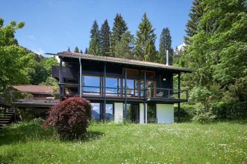 uma casa com grandes janelas de vidro num campo em Alpenchalet Walchensee em Walchensee