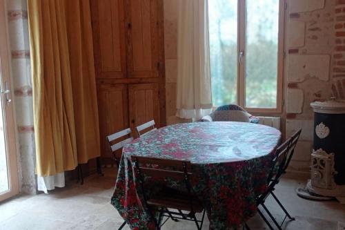 einen Tisch und Stühle in einem Zimmer mit Fenster in der Unterkunft Maison au bord d'un ruisseau in Pontigné