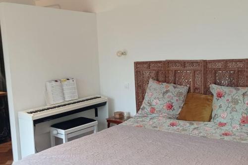 ein Schlafzimmer mit einem Bett und einem Klavier in der Unterkunft Maison au bord d'un ruisseau in Pontigné