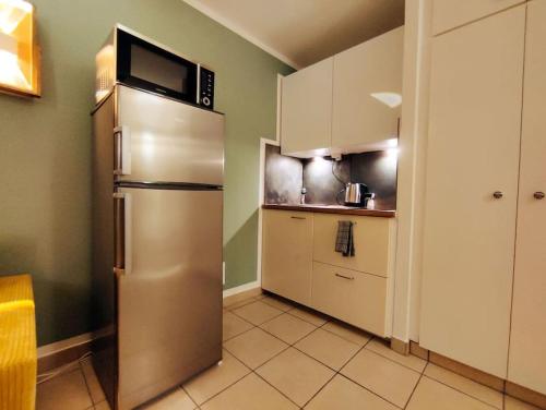 eine Küche mit einem Kühlschrank aus Edelstahl und einer Mikrowelle in der Unterkunft 6 min zum Hauptbahnhof, kostenfrei parken, cozy in Mainz