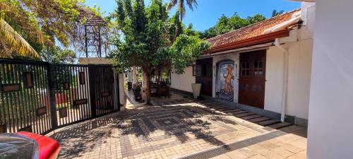 um portão para um edifício com uma árvore ao lado em Amanda Mirissa em Mirissa