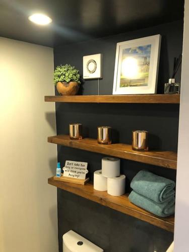 a bathroom with wooden shelves with towels and a clock at Studio 77 - Stylish, Free Parking, Fast Wi-Fi, Netflix in Sheffield