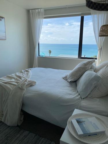 a bedroom with a bed with a view of the ocean at Ahipara Beach Pad in Ahipara