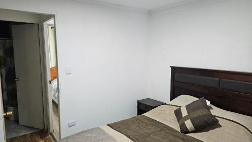 a bedroom with a bed with a wooden headboard at Departamento con Piscina y Estacionamiento in Chillán