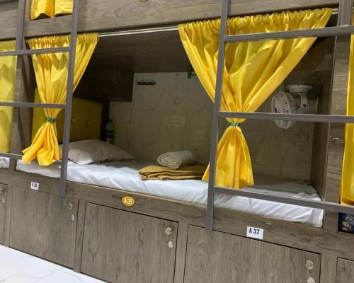 a bunk bed with yellow curtains in a room at Neenava Dormitory Asalpha in Mumbai