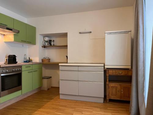 eine Küche mit grünen Schränken und einem weißen Kühlschrank in der Unterkunft Obersdorfer Hof in Bad Mitterndorf