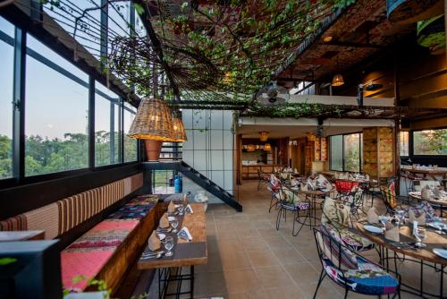 un restaurante con mesas, sillas y ventanas en White Moon Hotel, en Gampaha