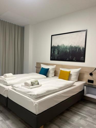 - une chambre avec un grand lit blanc et des oreillers colorés dans l'établissement Stargaze Forum Hotel Düsseldorf-Hilden, à Hilden