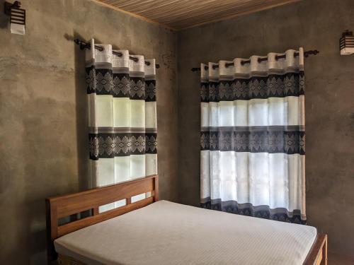 een slaapkamer met een bed en een raam met gordijnen bij Afenta Hotel - Mihintale in Mihintale