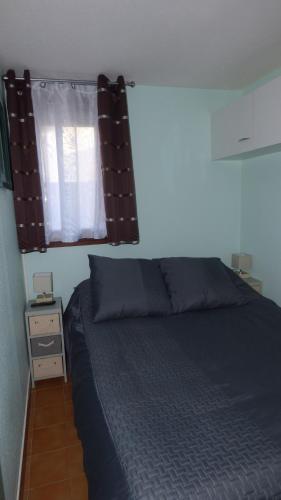 une chambre avec un lit bleu et une fenêtre dans l'établissement T2, rez-de-jardin, terrasse, piscine, Les Maisons de la Plage, Narbonne Plage, à Narbonne-Plage