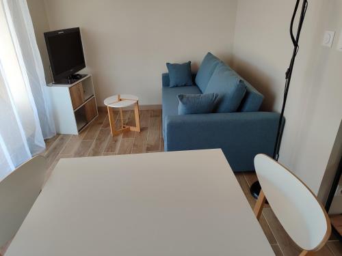 a living room with a blue couch and a tv at Maison d'hôtes calme proche village in Bédoin