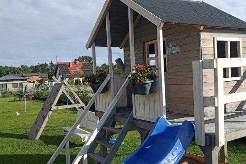 a small wooden play house with a slide at Comfortable premium class apartment shared swimming pool Gaski in Gąski