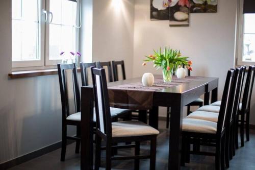 a dining room with a table and chairs with flowers on it at Comfortable premium class apartment shared swimming pool Gaski in Gąski