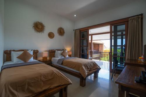 a bedroom with two beds and a balcony at Wiras Village in Canggu