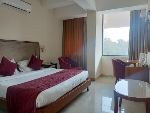 um quarto de hotel com uma cama, uma mesa e uma janela em zoz Chandigarh em Chandīgarh