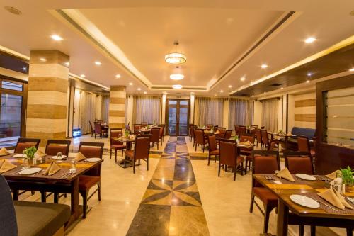 a restaurant with tables and chairs in a room at Amantra Comfort Hotel in Udaipur