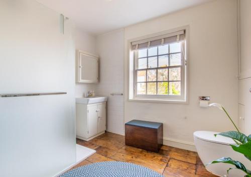 a bathroom with a sink and a toilet and a window at Celebration Cottage - Southwold in Southwold
