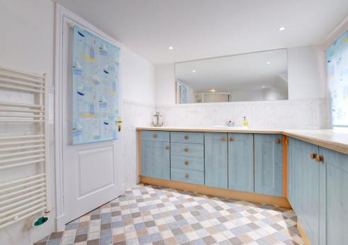 a bathroom with blue cabinets and a sink and a mirror at Riversea Cottage in Dartmouth