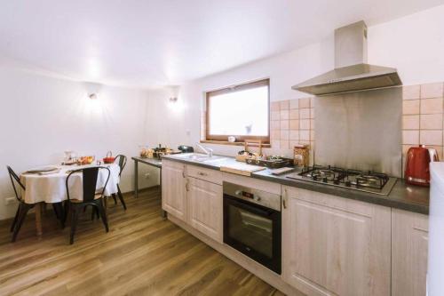 une cuisine avec une cuisinière et une table à l'intérieur dans l'établissement La Petite Maison, à Bonvillard
