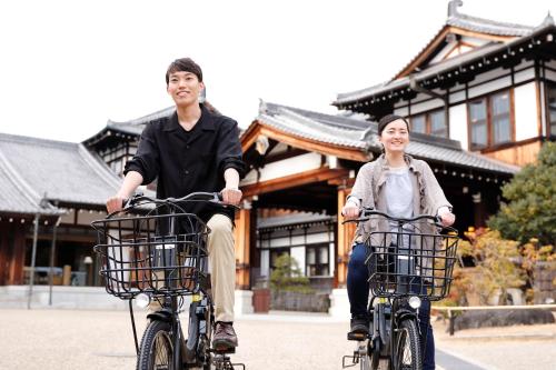 a man and woman riding bikes in front of a building at Nara Hotel in Nara