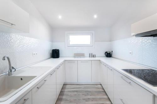 a white kitchen with white cabinets and a window at Dimar Apartments in Olympiada