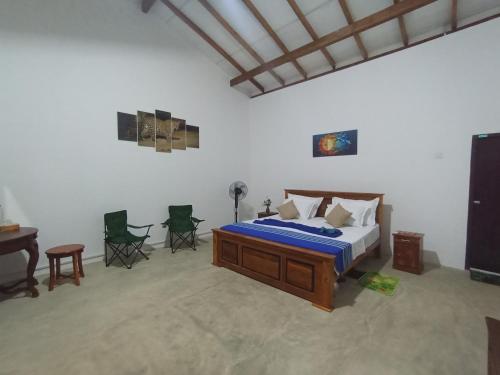 a bedroom with a bed and a desk and chairs at WILAPTTU WILD VILLA in Pahala Maragahawewa