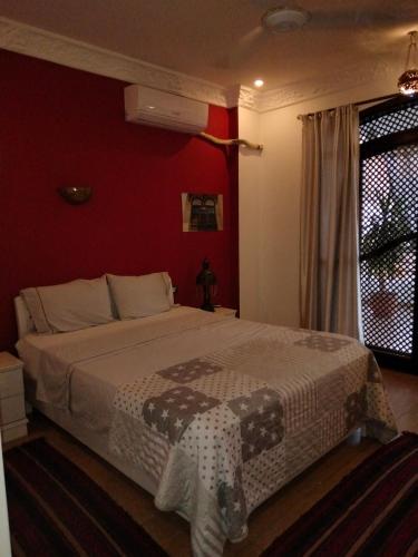 1 dormitorio con 1 cama grande y pared roja en Villa Quiet Place en Luxor