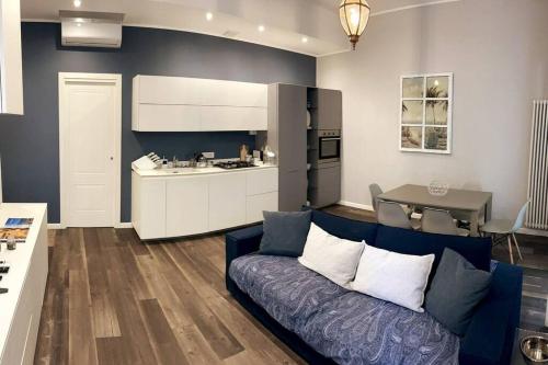 a living room with a blue couch and a kitchen at Nuovo Appartamento Borgo Coscia in Alassio