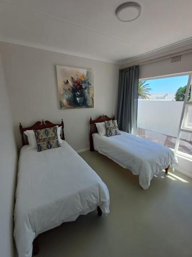 two beds in a room with a window at Versveld Cottage in Yzerfontein