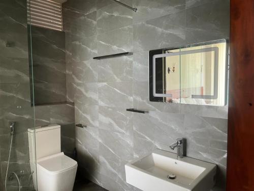 een badkamer met een wastafel, een toilet en een spiegel bij Blue Wave Beach Villa by Aaryan Group in Ambalangoda