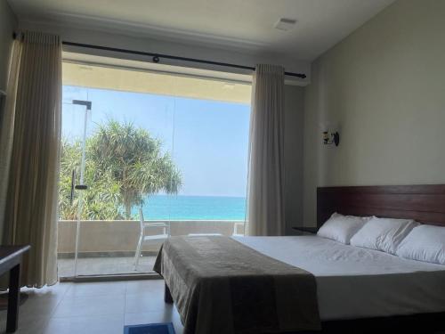 een slaapkamer met een bed en uitzicht op de oceaan bij Blue Wave Beach Villa by Aaryan Group in Ambalangoda