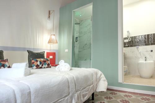 a bedroom with a large white bed and a bathroom at Le Dame di Sicilia Sicilian Vintage Rooms in Palermo