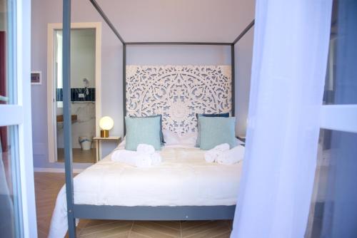 a bedroom with a canopy bed with blue pillows at Le Dame di Sicilia Sicilian Vintage Rooms in Palermo