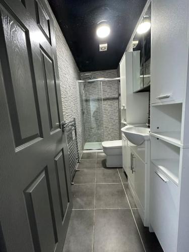 a bathroom with a shower and a toilet and a door at Modern 2 Bed Flat In Derby City in Derby
