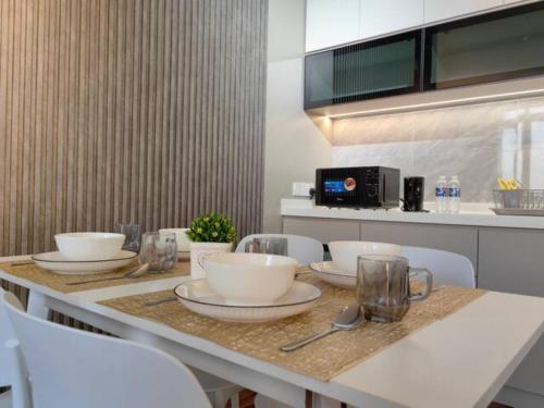 a table with bowls and plates on it in a kitchen at Near Airport K Avenue Family Room in Donggongon