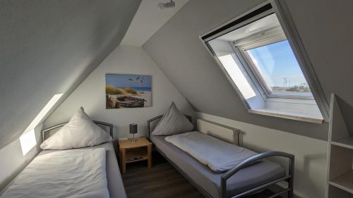 a attic room with two beds and a window at Dachgeschosswohnung mit Pool in Nordleda