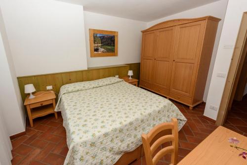 1 dormitorio con 1 cama y armario de madera en Agritur La Pieve, en Taio