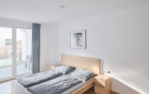 Bett in einem weißen Zimmer mit Fenster in der Unterkunft Wohnen in Wattens Top 2 in Wattens