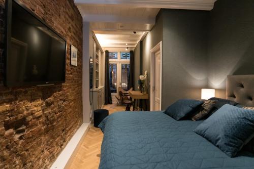 a bedroom with a blue bed and a brick wall at B&B Felix in Amsterdam