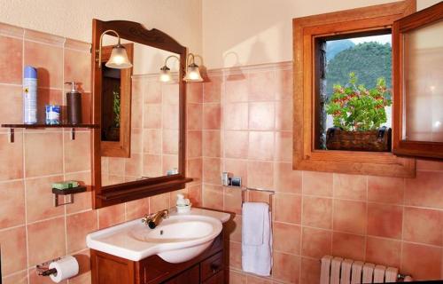 baño con lavabo, espejo y ventana en Paller Cal Cintet en Aristot