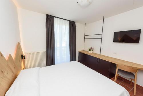 a bedroom with a bed and a desk and a television at Agritur La Pieve in Taio