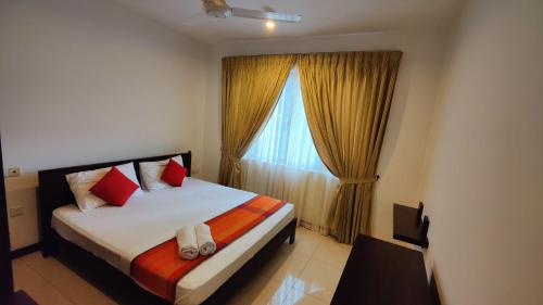 a bedroom with a bed with red pillows and a window at Cozy 2 BR Apartment with pool by Ceylon Vacation in Colombo